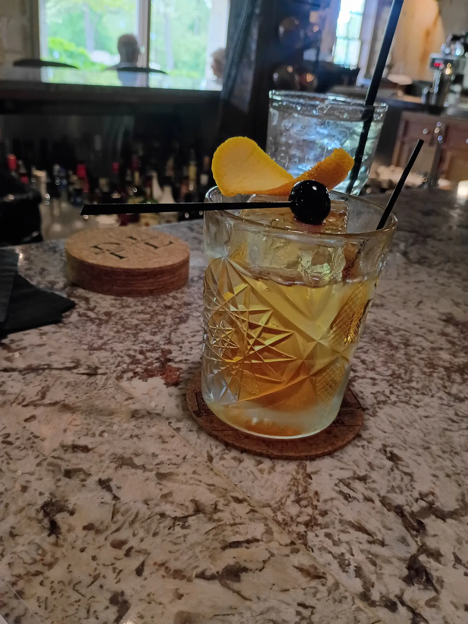 Custom branded cork coaster at bar counter with cocktails and glassware